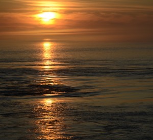 As the tide ebbs, the sun sets through the fog reflected in the boils and rips.